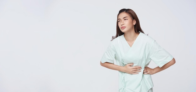 Foto gratuita paciente mujer asiática infeliz que parece enferma sufre de dolor de estómago aislado sobre fondo blanco debido a la menstruación y comer alimentos en mal estado gastritis crónica