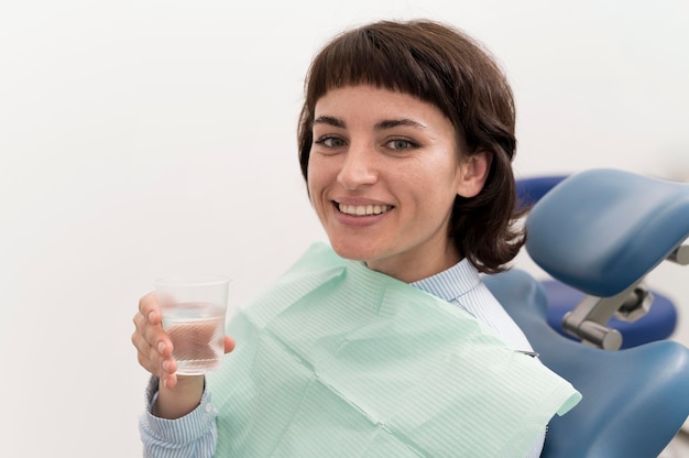 Paciente de sexo femenino, agua potable en el consultorio del dentista antes del procedimiento dental