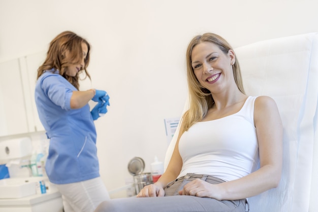 Paciente de sexo femenino joven sonriente que espera al médico que prepara una aguja de la jeringa