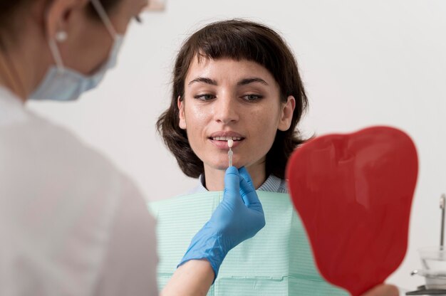 Paciente de sexo femenino que mira en el espejo en la oficina del dentista