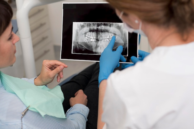 Paciente de sexo femenino que mira la radiografía de sus dientes con el dentista