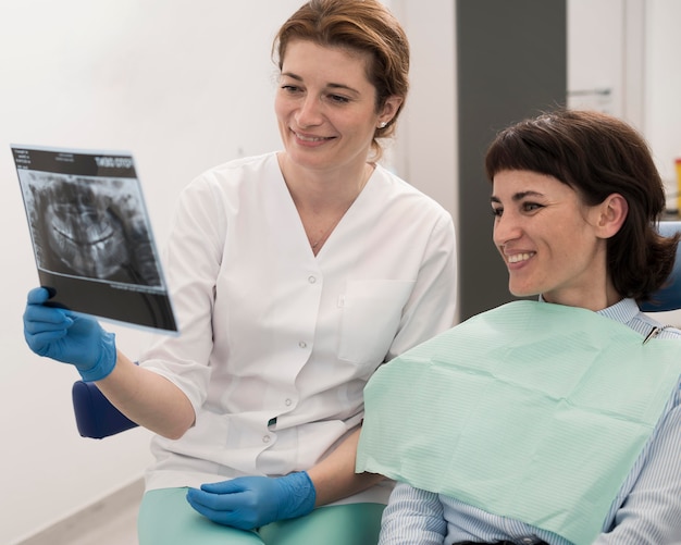 Paciente de sexo femenino que mira la radiografía de sus dientes con el dentista