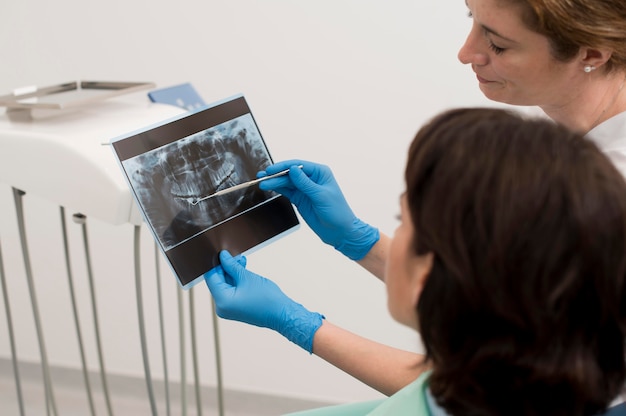 Paciente de sexo femenino que mira la radiografía de sus dientes con el dentista