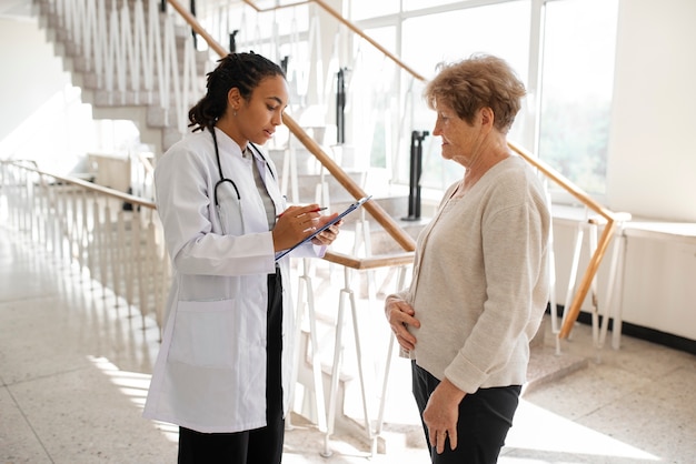 Foto gratuita paciente de tiro medio y médico en la clínica.