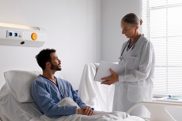 Foto gratuita paciente varón enfermo en la cama hablando con una enfermera