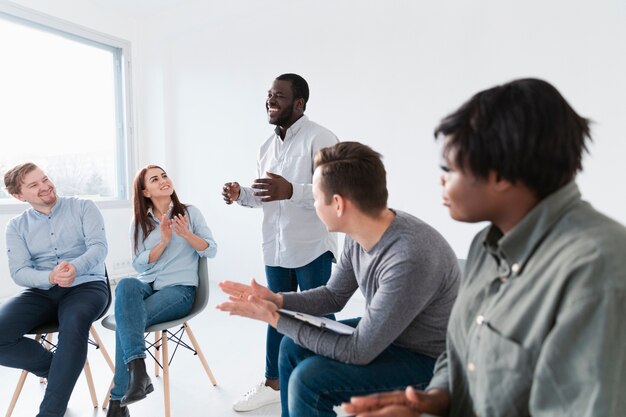 Pacientes de rehabilitación aplaudiendo a hombre afroamericano