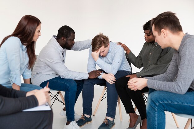 Pacientes de rehabilitación consolando a un hombre triste