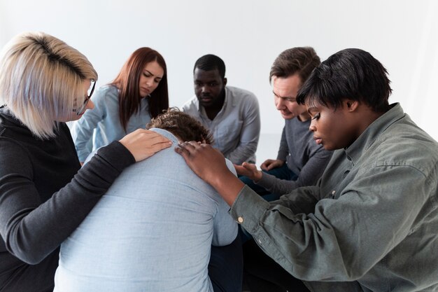 Pacientes de rehabilitación consolando a un hombre triste