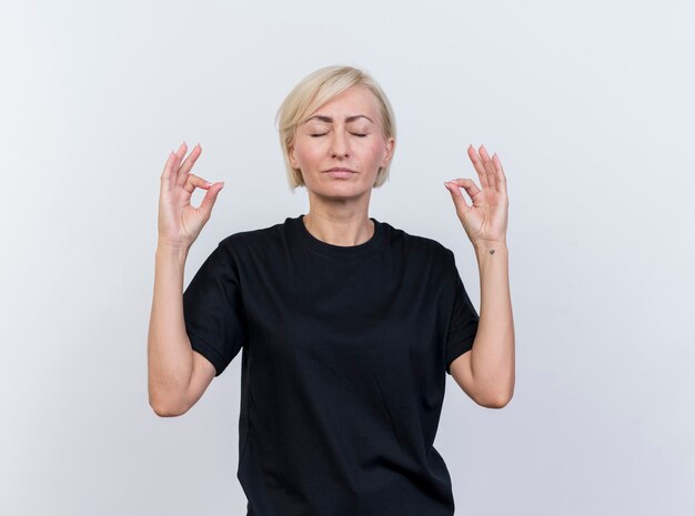 Pacífica mujer eslava rubia de mediana edad meditando con los ojos cerrados aislado sobre fondo blanco con espacio de copia