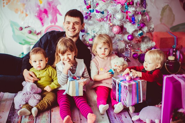 El padre abrazando a sus hijos cerca del árbol de Navidad