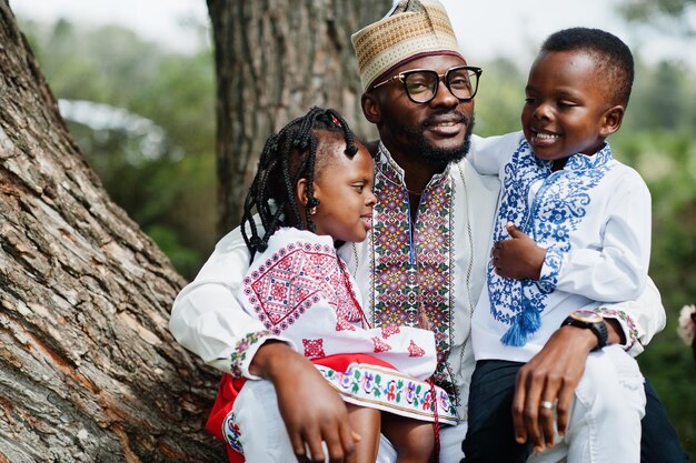 Padre africano con niños vestidos con ropa tradicional en el parque