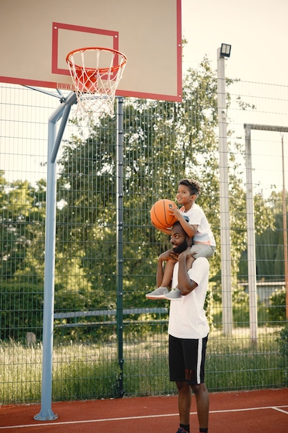 padre afroamericano jugando bascketball con su hijo