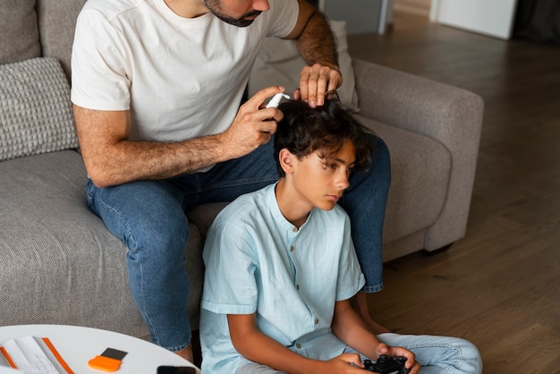 Foto gratuita padre de alto ángulo aplicando tratamiento para piojos