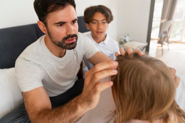 Padre de alto ángulo ayudando a niña con piojos