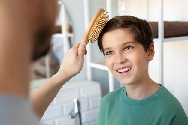 Padre de alto ángulo cepillando el cabello de un niño sonriente