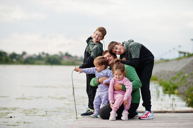 Padre ama a papá con cuatro hijos al aire libre en el muelle Deportes familia numerosa pasa tiempo libre al aire libre