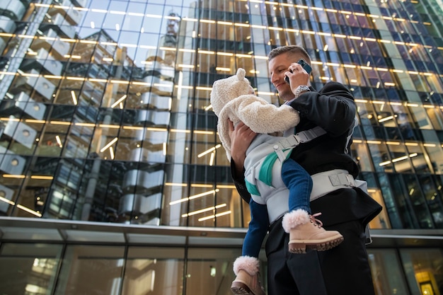 Foto gratuita padre de ángulo bajo con bebé en la ciudad