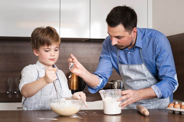 Padre de ángulo bajo enseñando a hijo a hacer masa