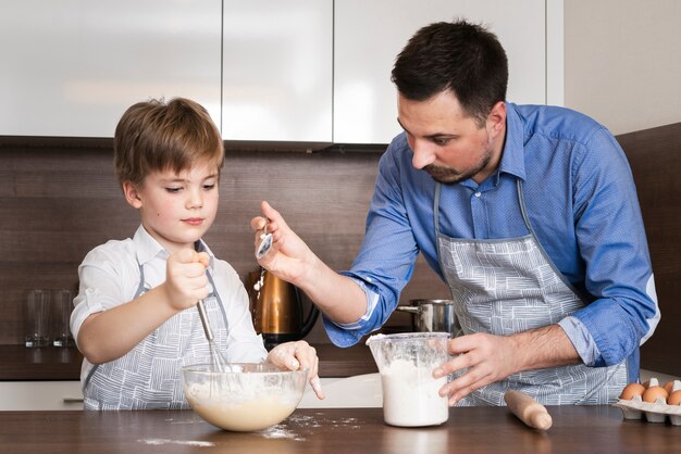 Padre de ángulo bajo enseñando a hijo a hacer masa