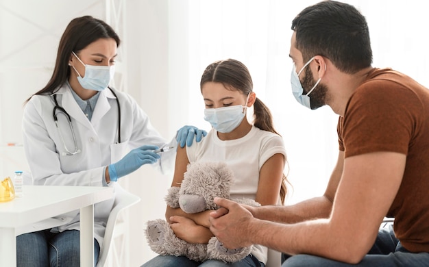 Foto gratuita padre apoyando a su hija que está siendo vacunada