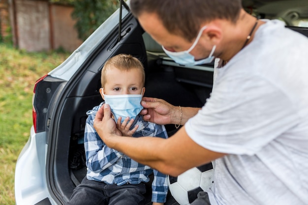 Foto gratuita padre arreglando la máscara médica de su hijo