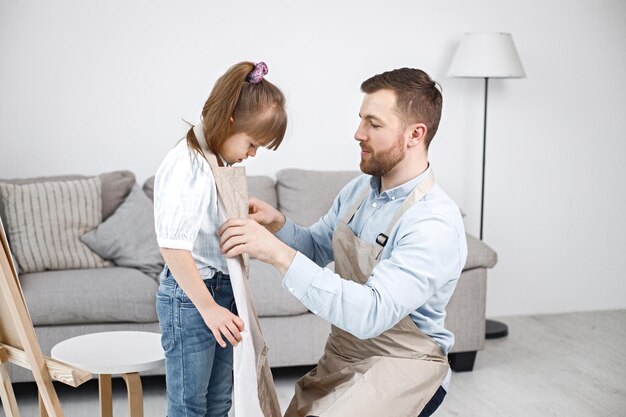 Padre ayudando a su hija con síndrome de Down a ponerse un delantal