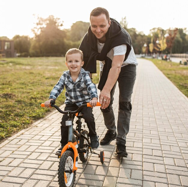 Padre ayudando a su hijo a andar en bicicleta