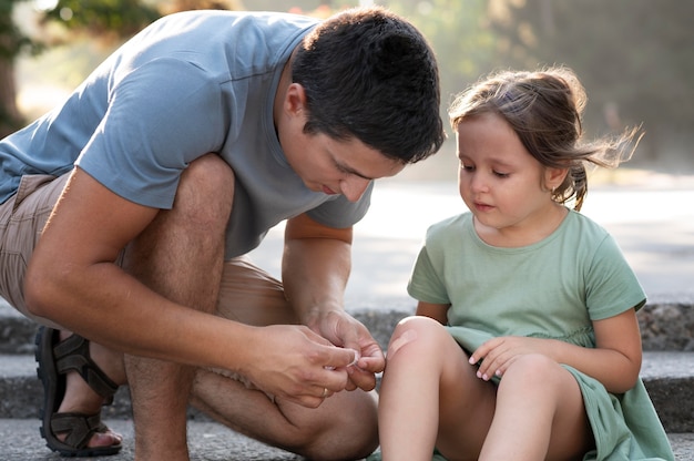 Foto gratuita padre ayudando a su hijo con lesión de rodilla