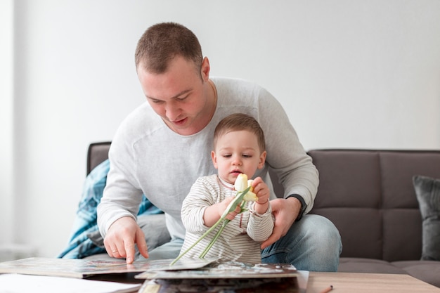 Foto gratuita padre y bebé con libro y flor