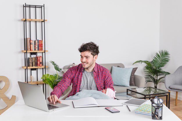 Padre, con, bebé, usar la computadora portátil, en el escritorio