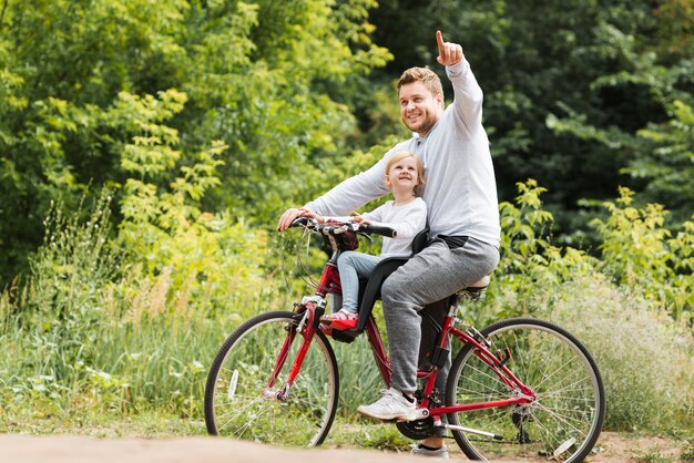 Padre en bicicleta apuntando para hija