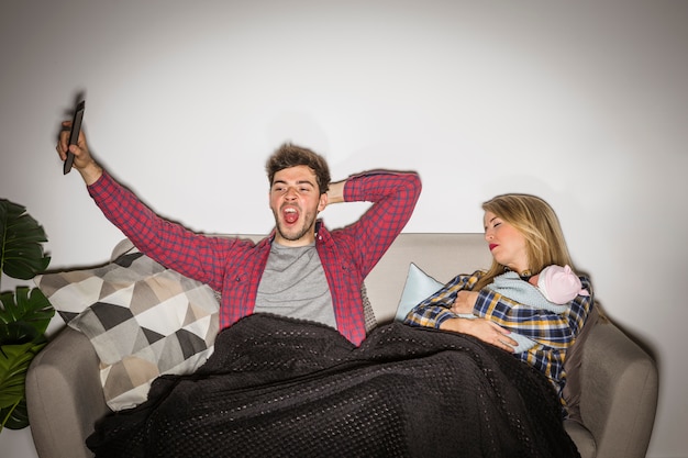 Foto gratuita padre cansado viendo televisión mientras la madre duerme