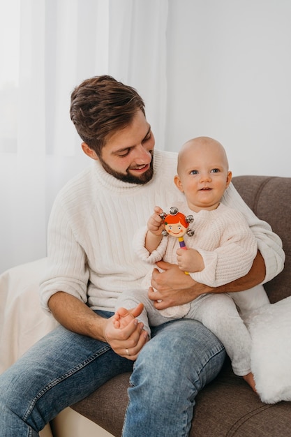 Foto gratuita padre en casa sosteniendo a su bebé