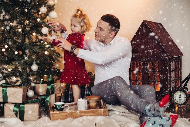 Padre caucásico ayuda a su hija a decorar el árbol de navidad