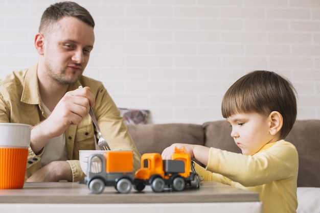 Foto gratuita padre comiendo y niño jugando