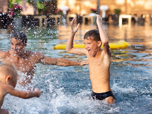 Padre disfrutando de un día con sus hijos en la piscina.