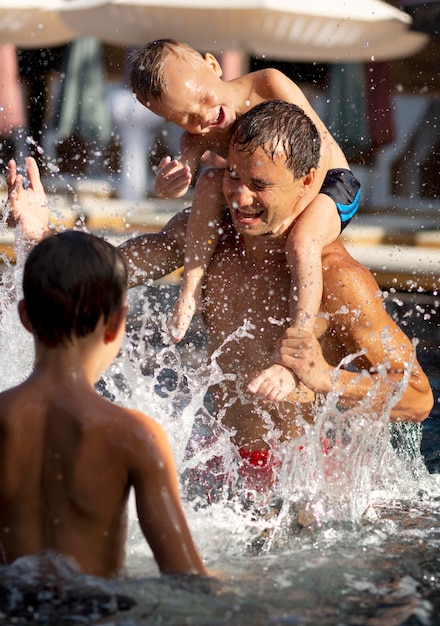 Padre disfrutando de un día con sus hijos en la piscina.