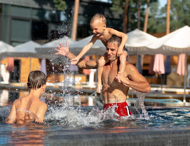 Padre disfrutando de un día con sus hijos en la piscina.