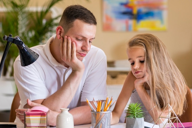 Foto gratuita padre e hija aburridos y haciendo tarea