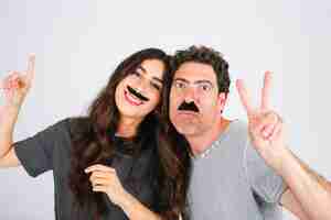 Foto gratuita padre e hija con bigotes artificiales que gesticulan la paz