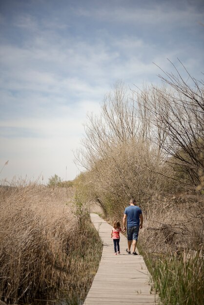 Padre e hija caminando en un camino de tablas de madera en un humedal, Granada, Andalucía
