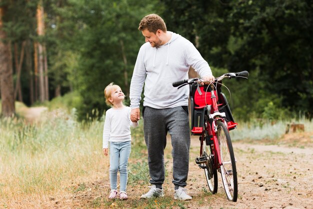 Padre e hija caminando junto a la bicicleta