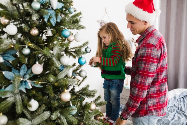 Padre e hija decorando árbol de navidad