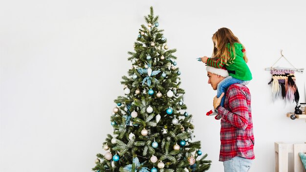 Padre e hija decorando árbol de navidad