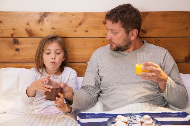 Padre e hija desayunando en la cama