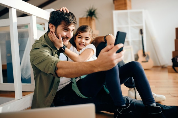 Padre e hija despreocupados tomando selfie en su nuevo hogar