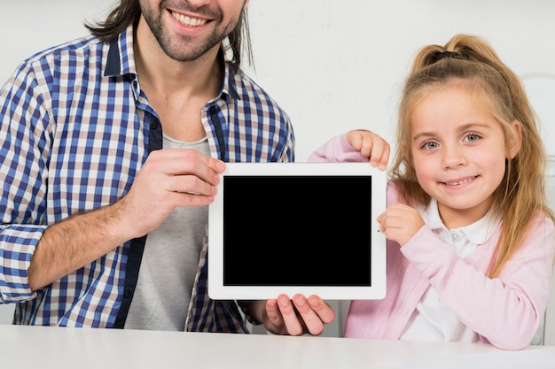 Padre e hija enseñando tablet