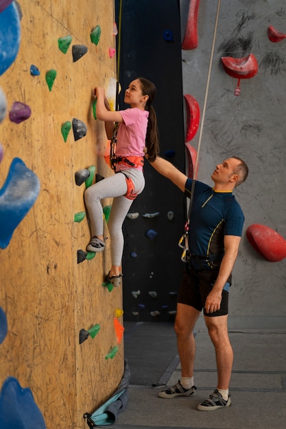 Foto gratuita padre e hija escalando juntos en el interior de la arena