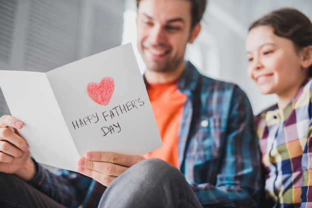 Padre e hija mirando a tarjeta en el día del padre