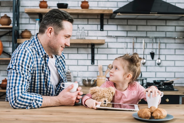 Padre e hija mirándose mientras toman café en la cocina